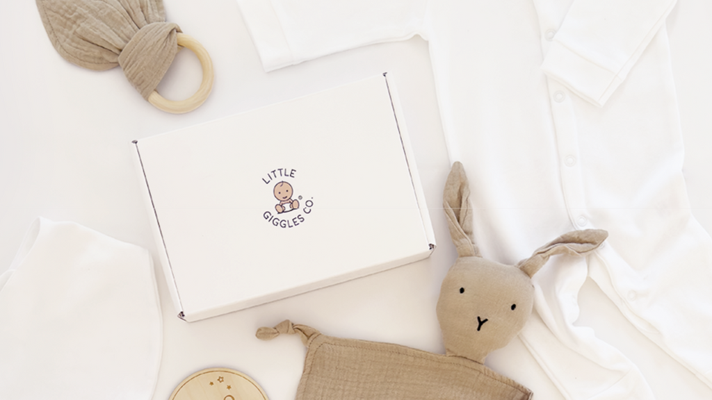 Little Giggles Co. neutral newborn gift box with newborn sleepsuit, dribble bib, sensory toy and a bunny comforter